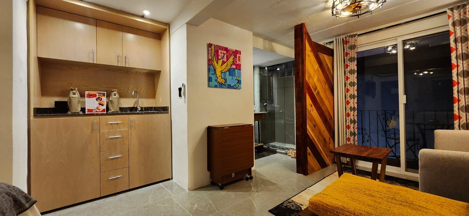 A small apartment kitchenette with a decorative wooden divider, with open sliding glass doors to a balcony.