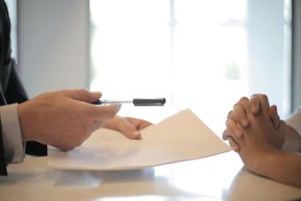image of person handing someone a contract