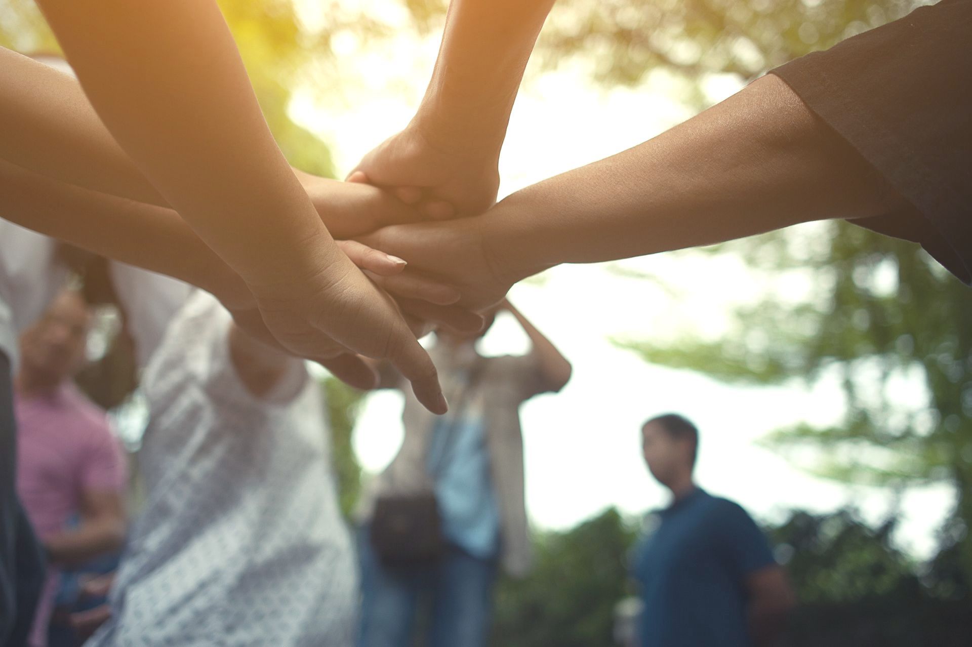 A group of people are putting their hands together in a circle.