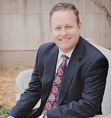 A man in a suit and tie is smiling for the camera