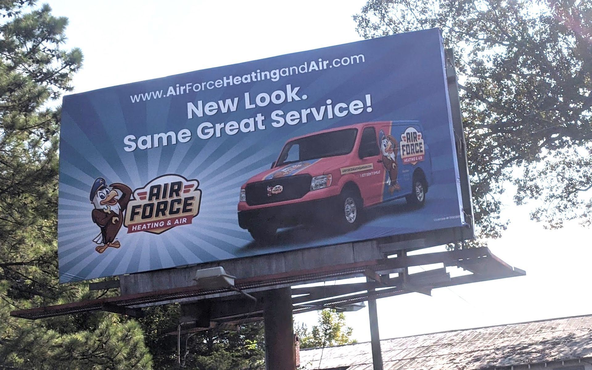 A red double decker bus is driving down a street next to a bus stop.
