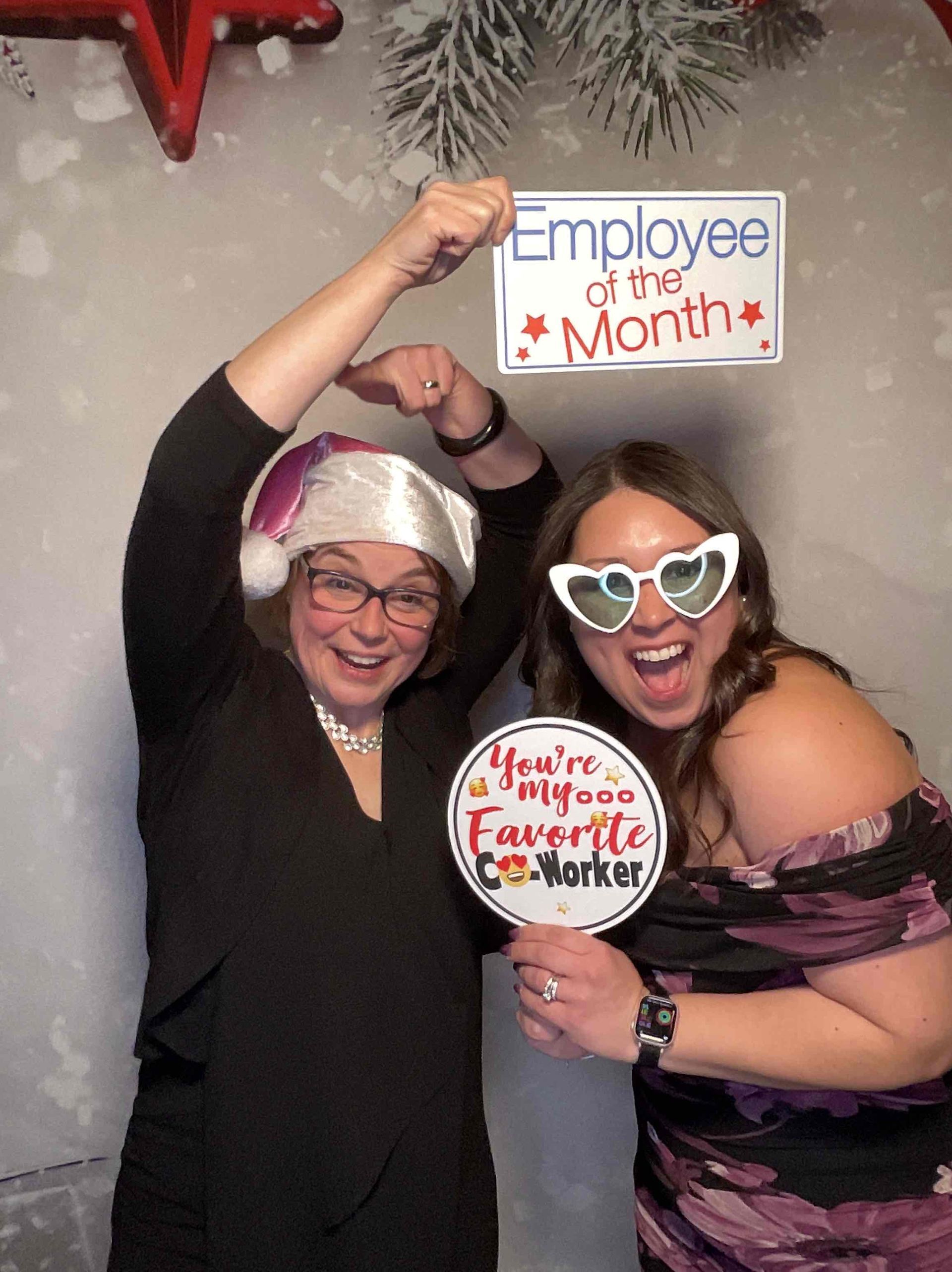 Two women are posing for a picture and one of them is wearing a santa hat.