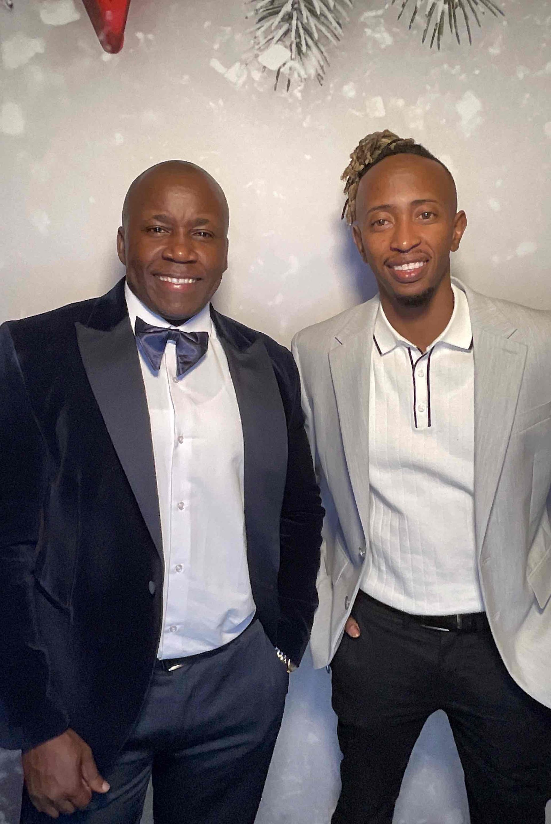 Two men in suits and bow ties are posing for a picture.