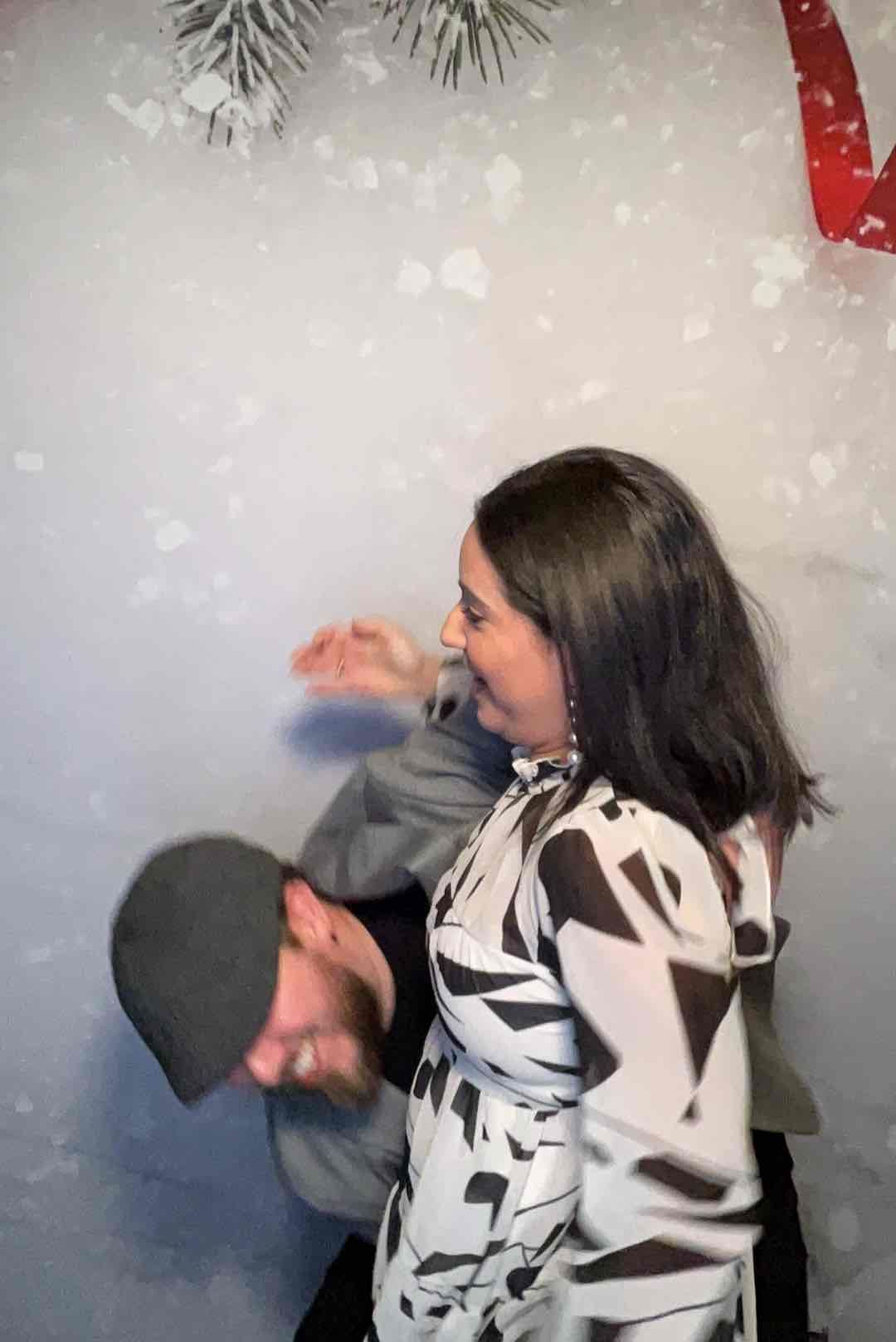 A man and a woman are standing next to each other in front of a snowy background.