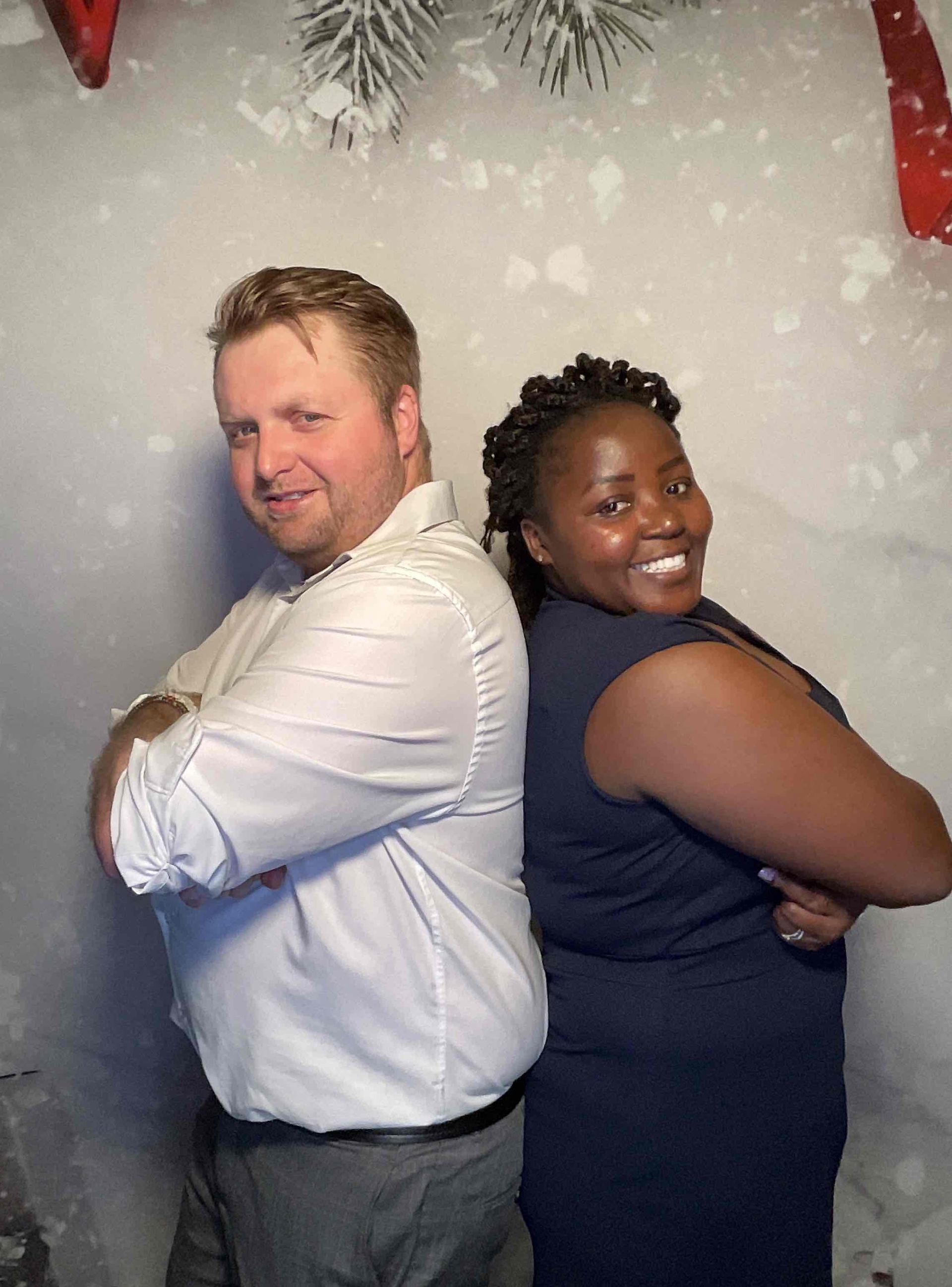 A man and a woman are standing back to back with their arms crossed.