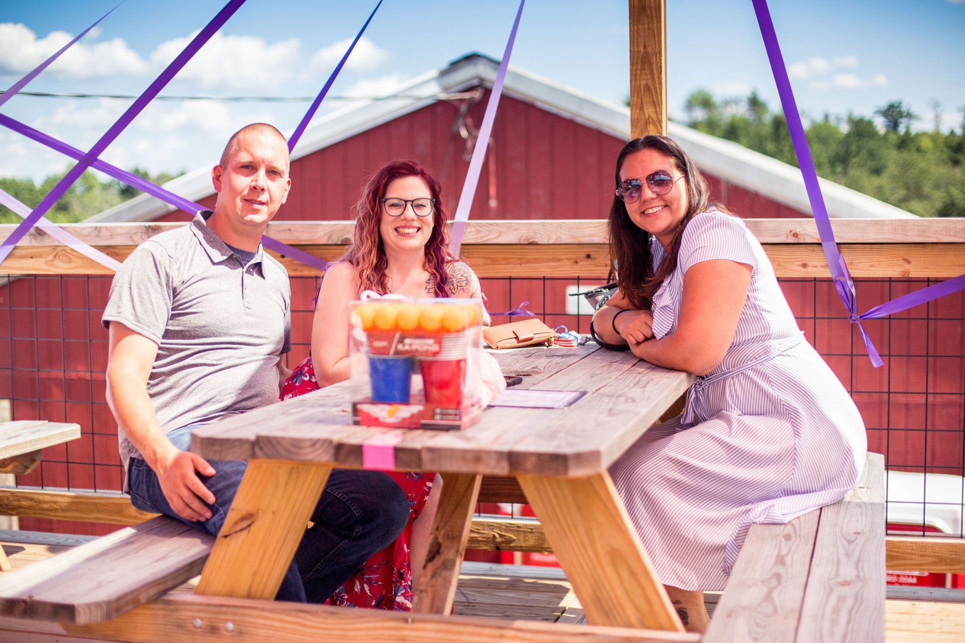 A man and two women are sitting at a picnic table.