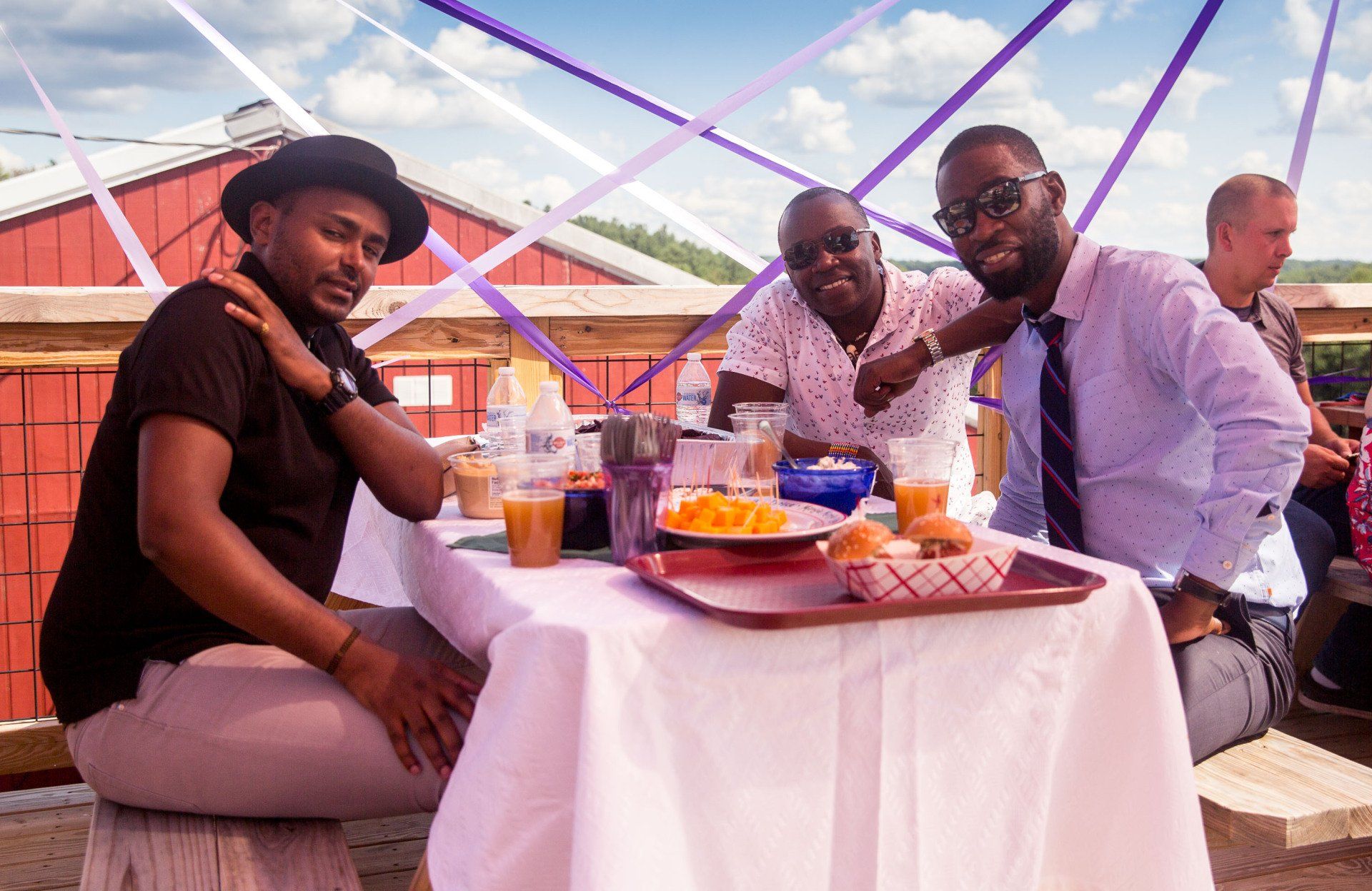 Three men are sitting at a table with a tray of food.