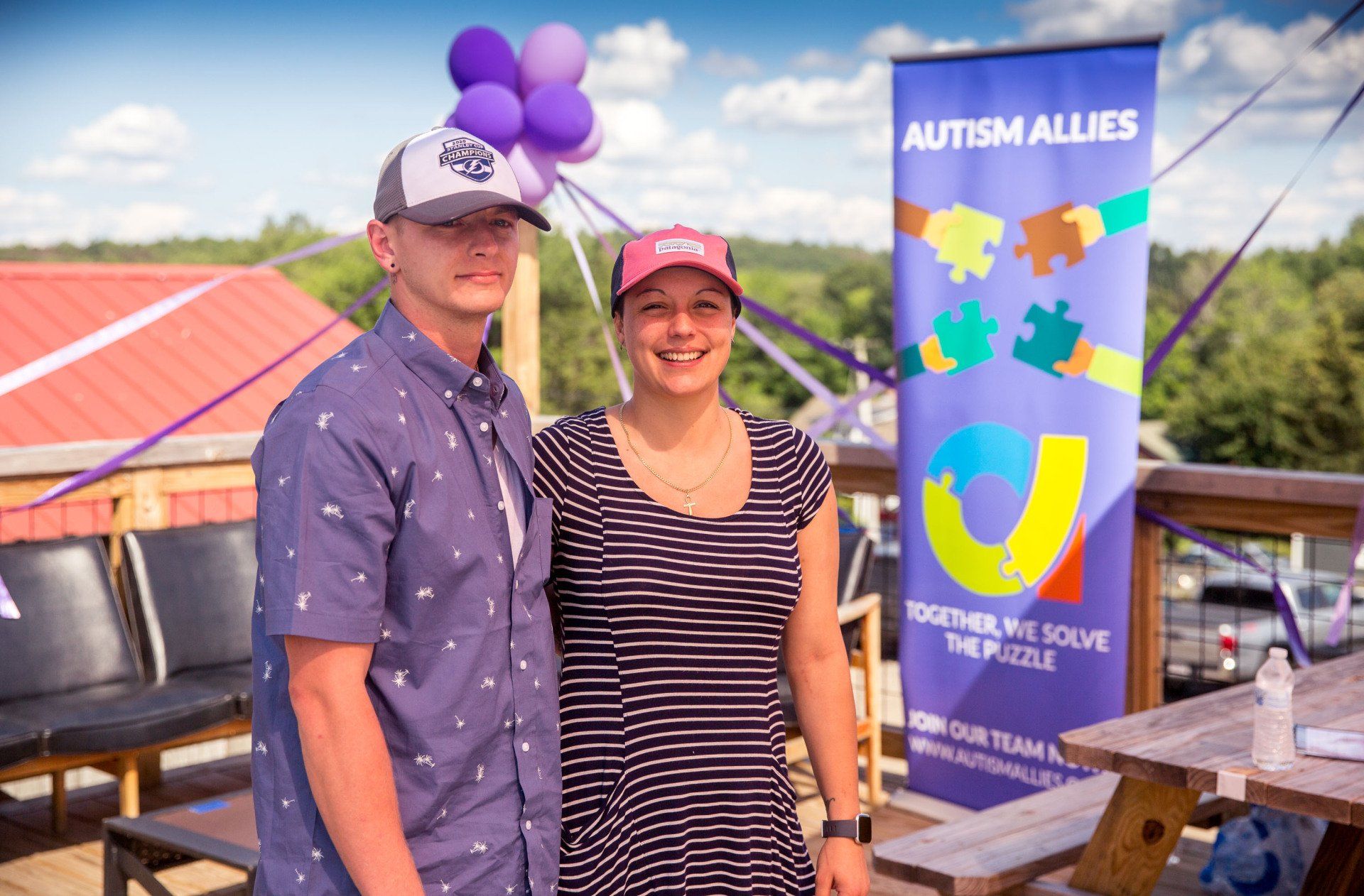 A man and a woman are standing next to each other in front of a sign that says autism allies.