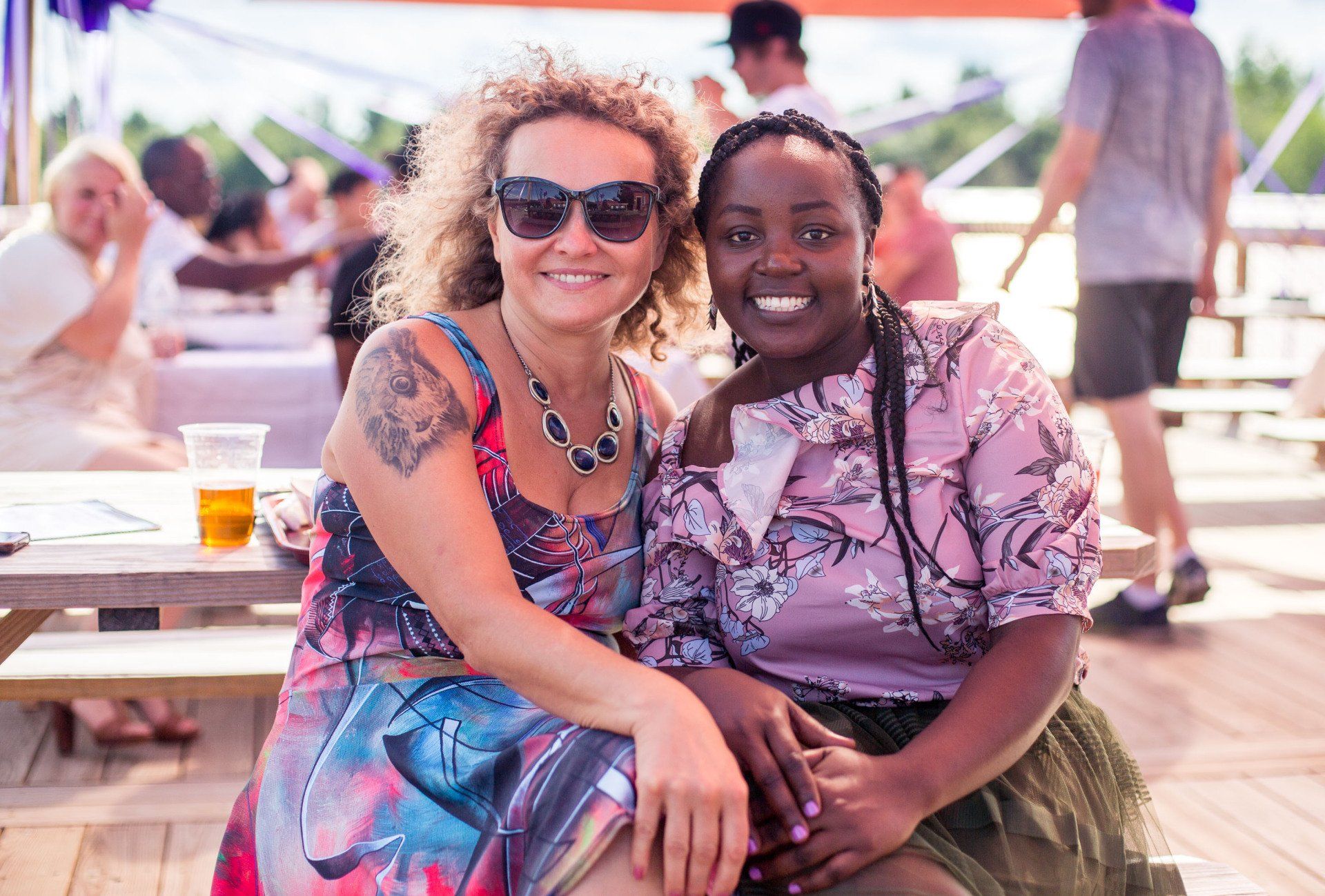 Two women are sitting next to each other at a picnic table.