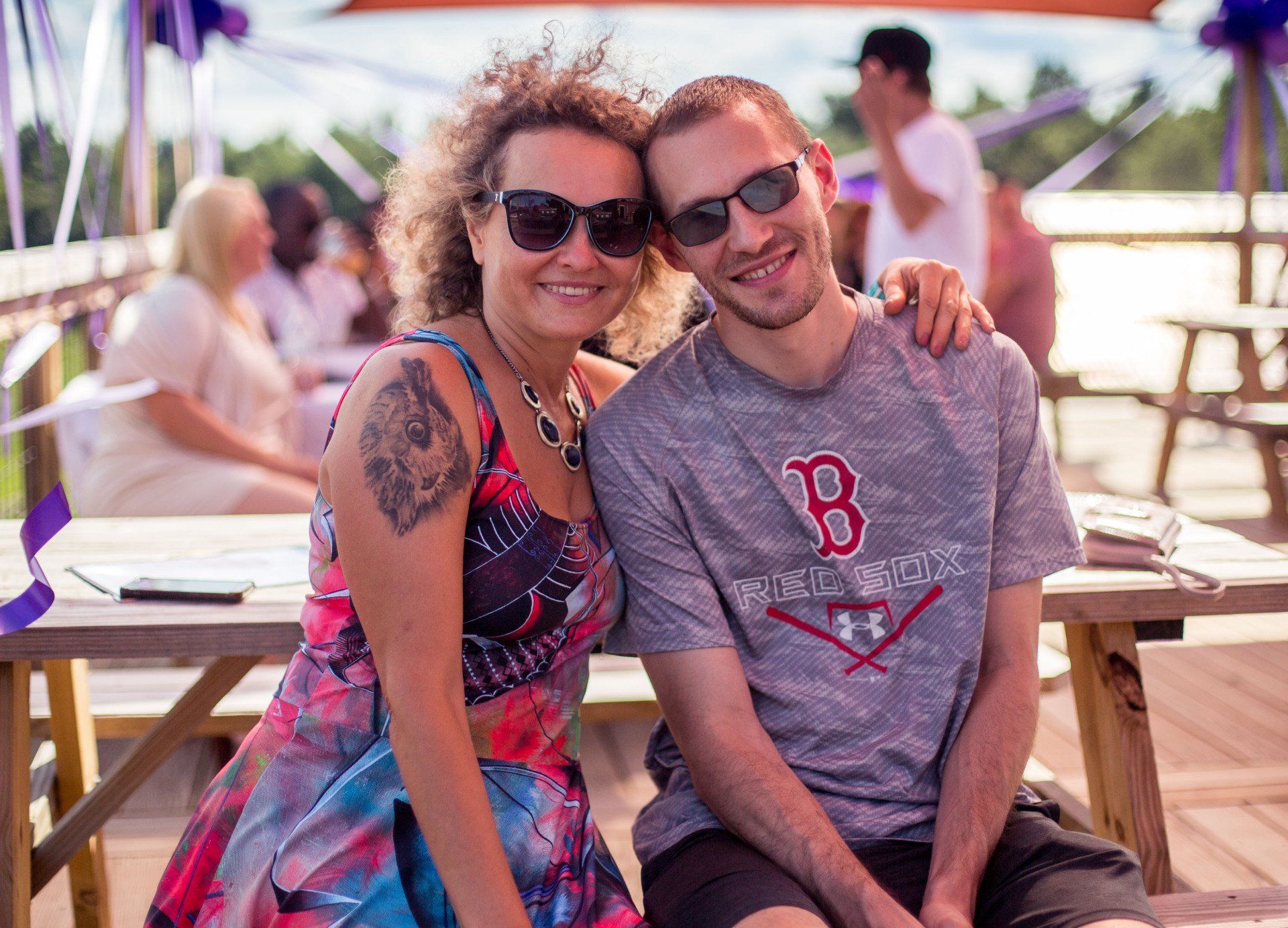 A man and a woman are posing for a picture while sitting at a picnic table.