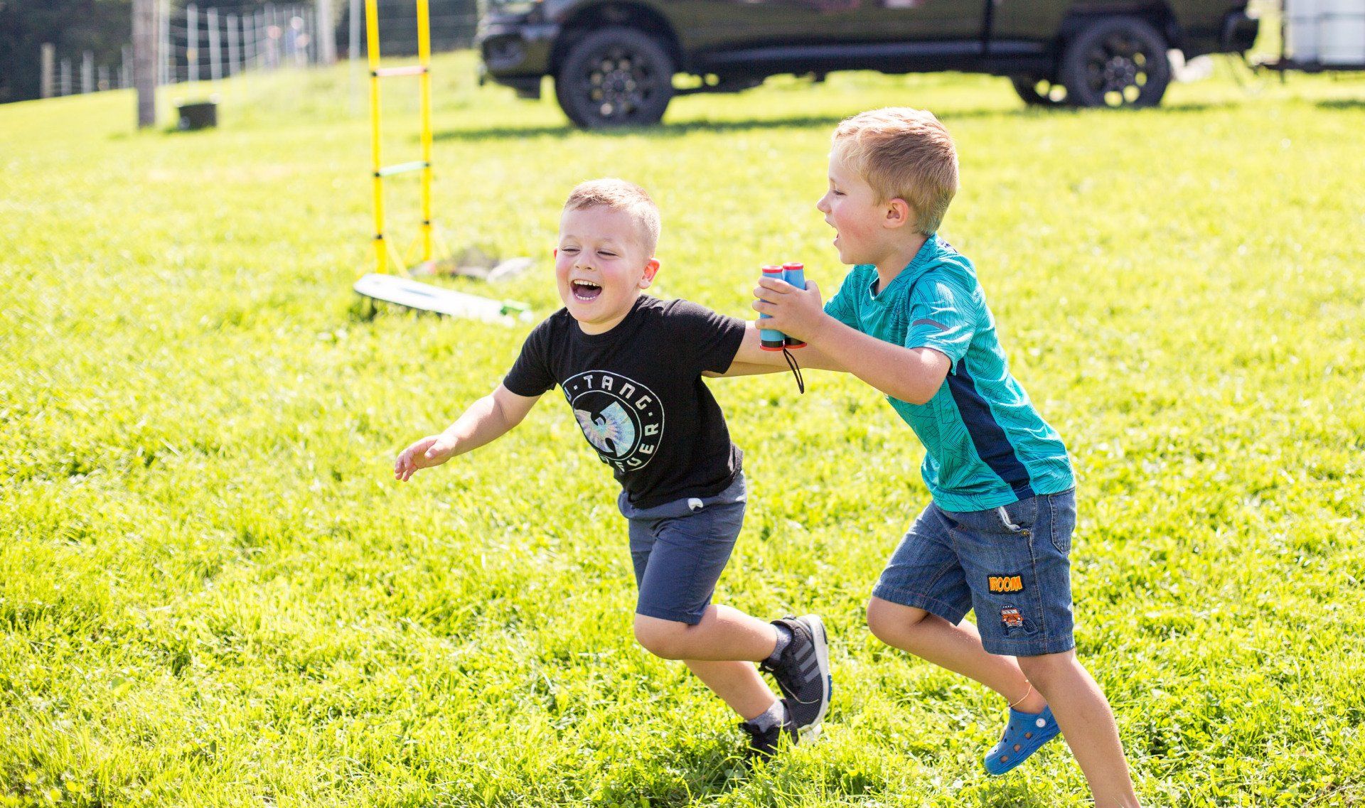 Two young boys are running in a grassy field.
