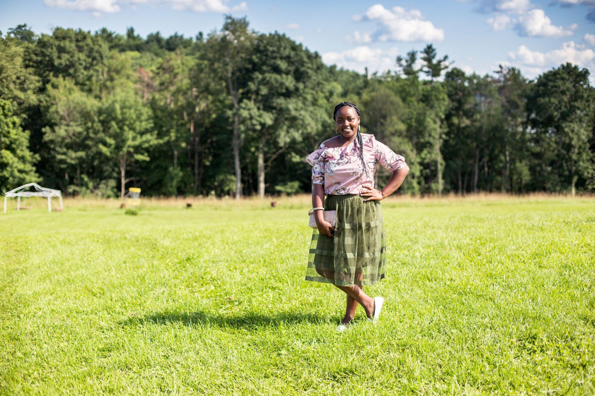 A woman is standing in a grassy field with her hands on her hips.