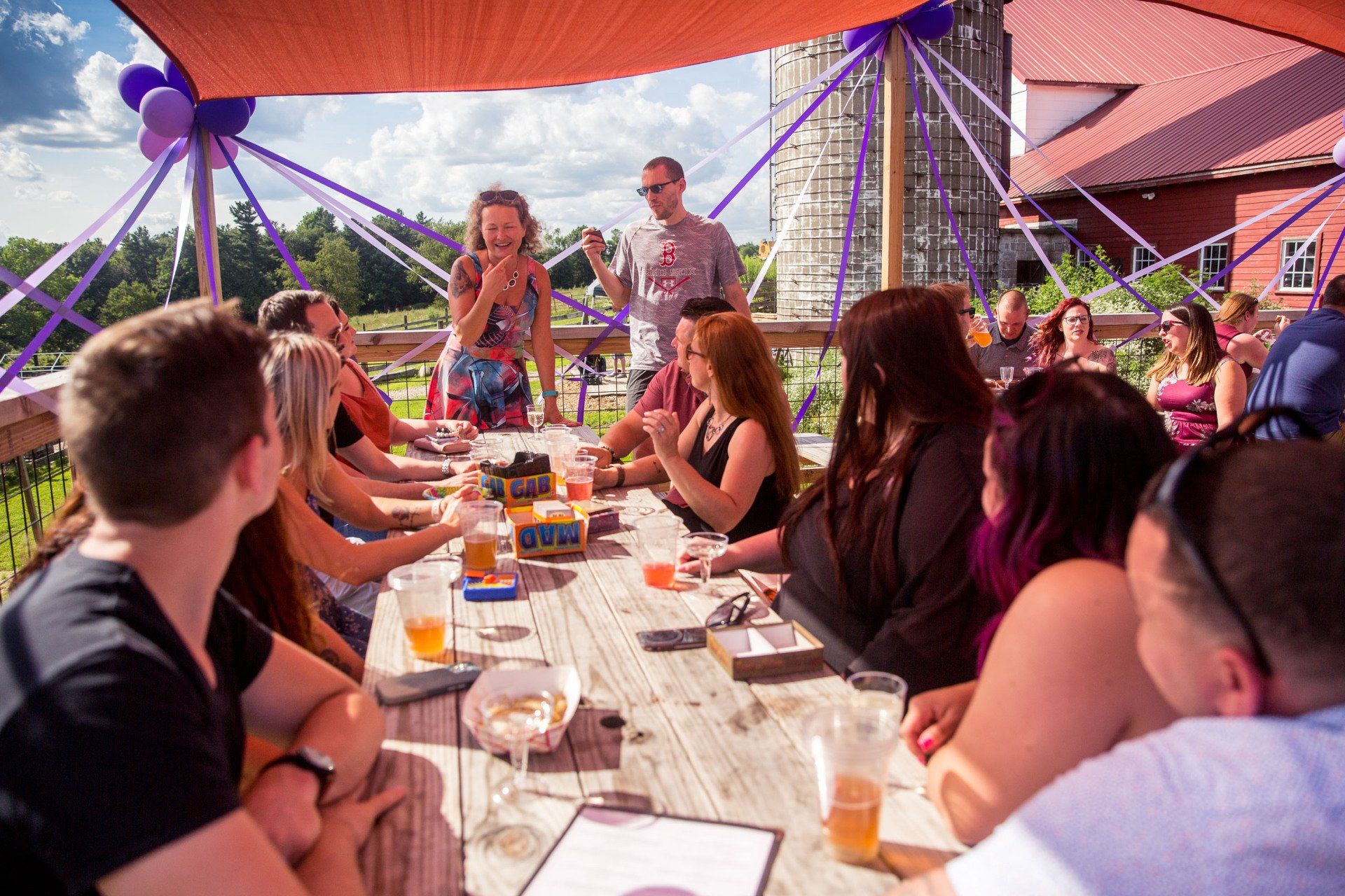 A group of people are sitting at a table under an umbrella.