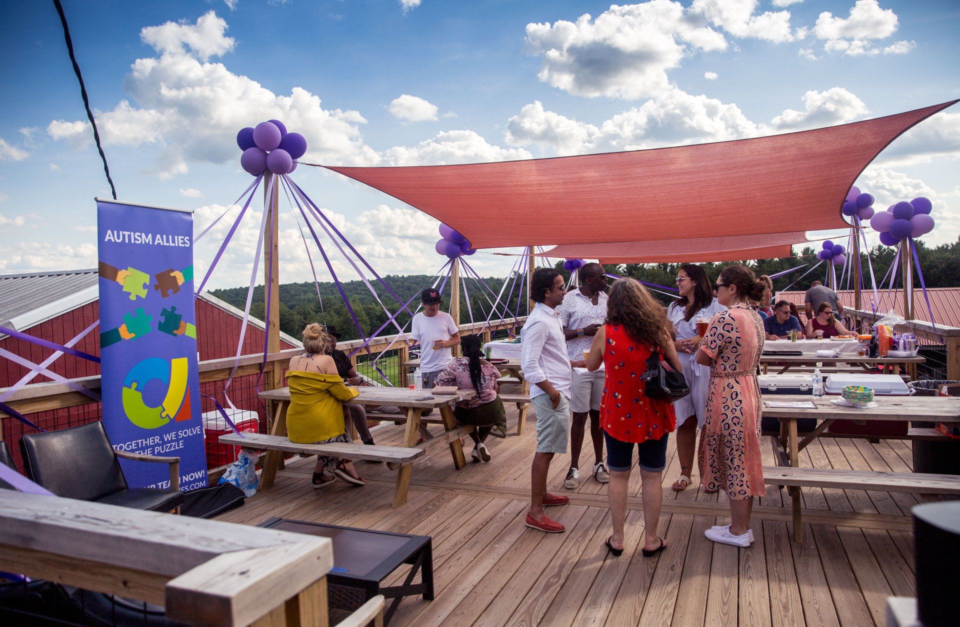 A group of people are standing on a wooden deck under a canopy.