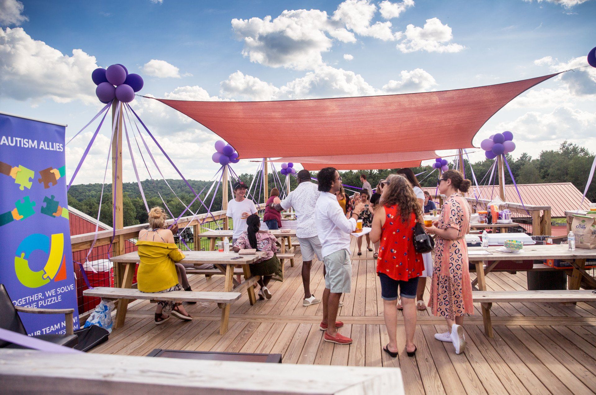 A group of people are standing on a wooden deck under a canopy.
