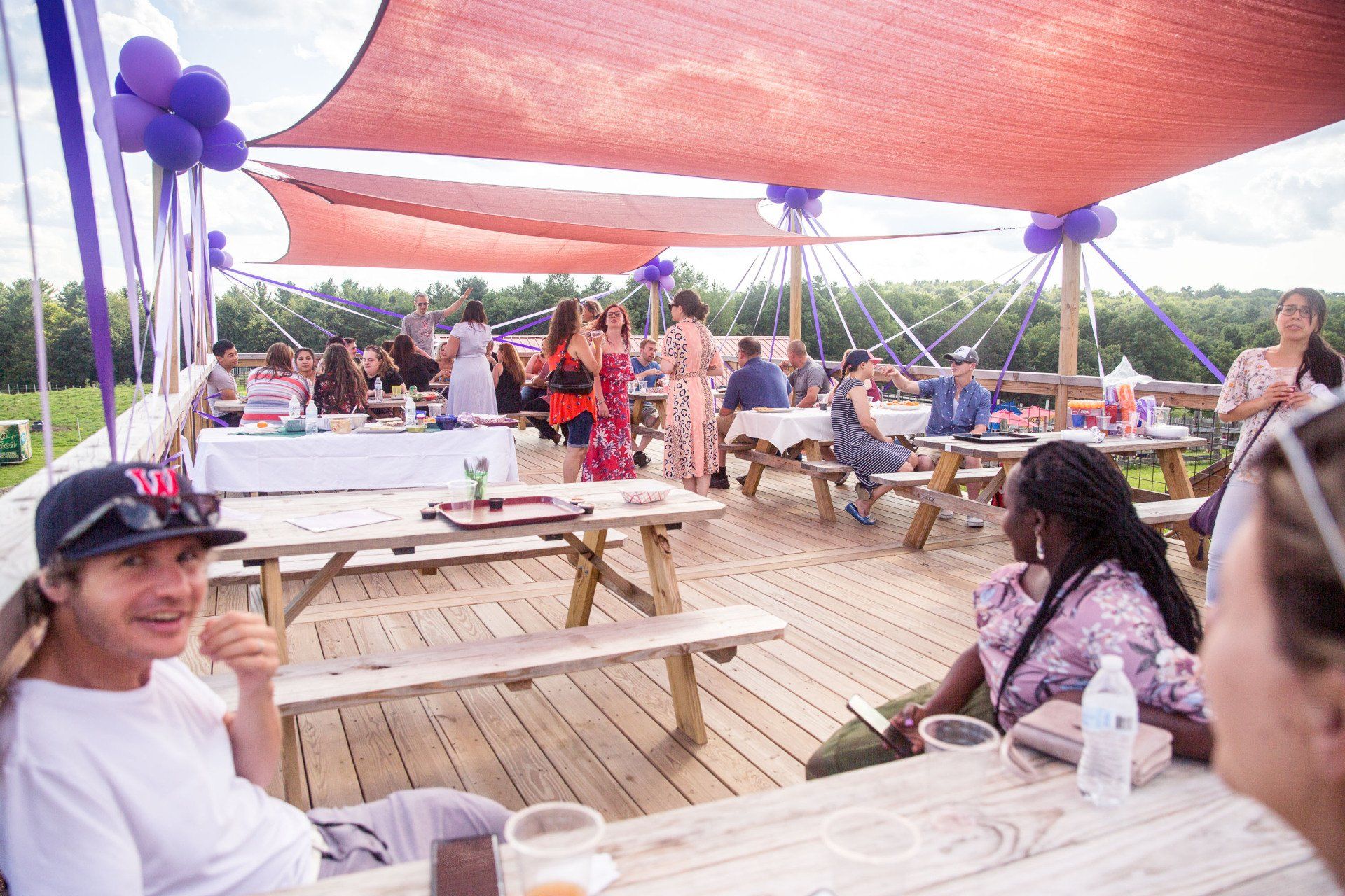 A group of people are sitting at picnic tables under a canopy.