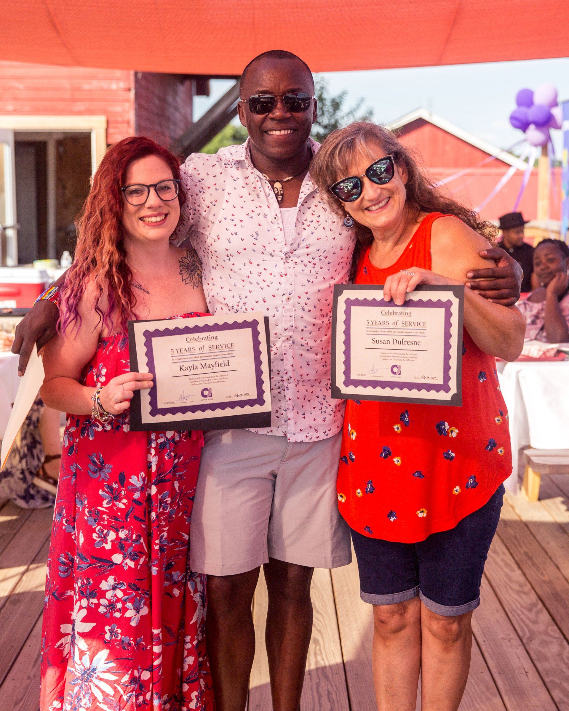A man and two women are posing for a picture while holding certificates.