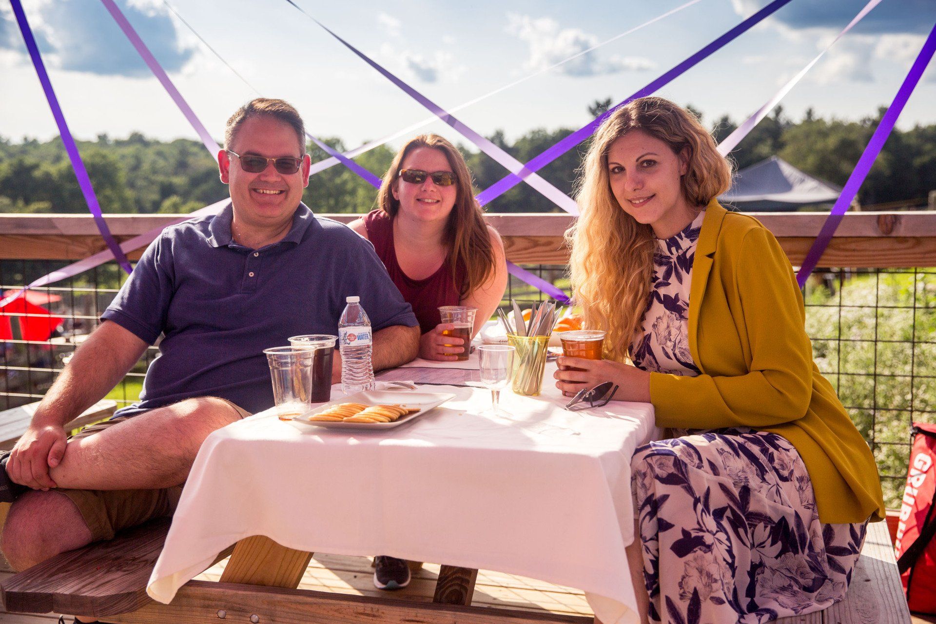 A man and two women are sitting at a picnic table.