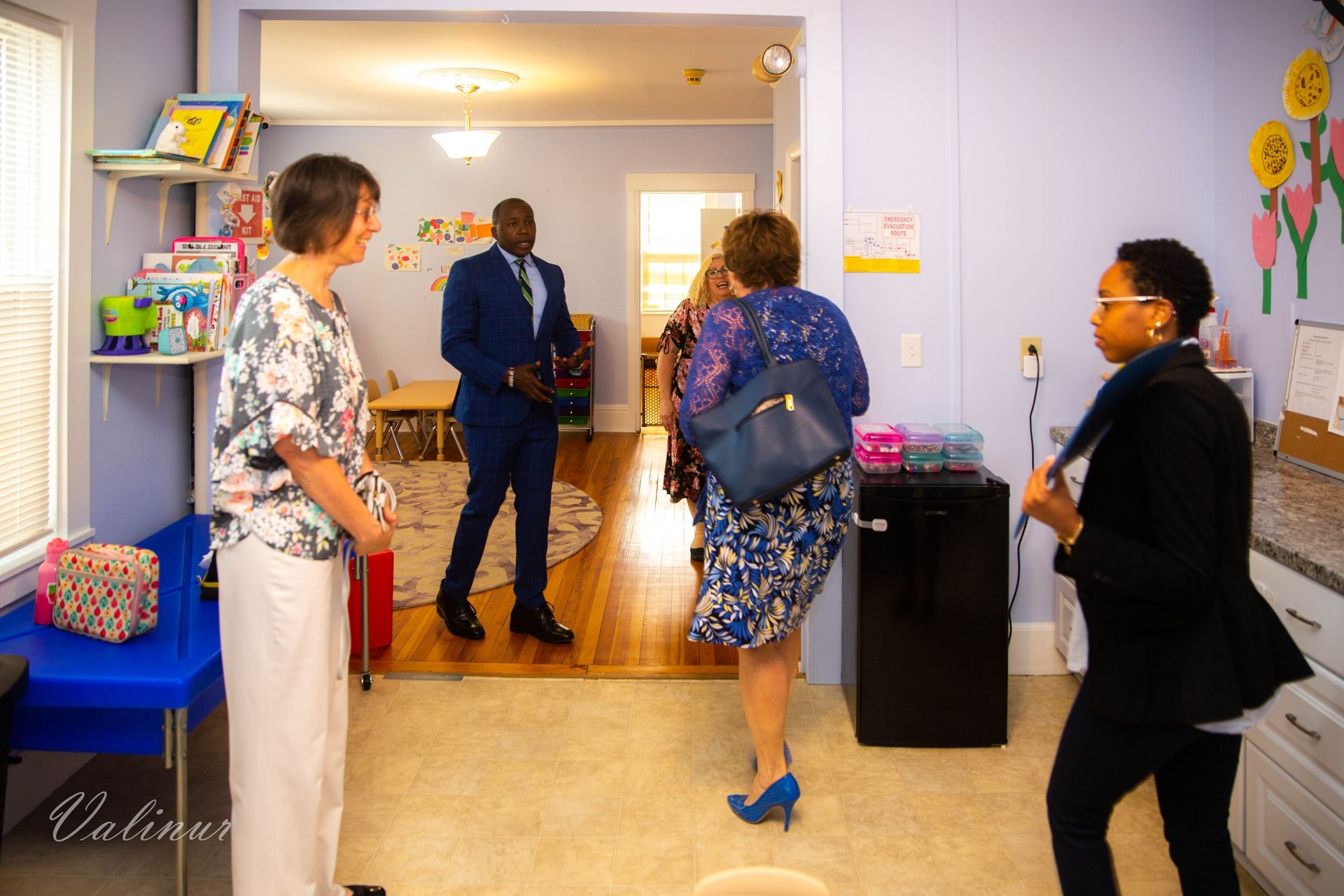 A group of people are standing in a room talking to each other.