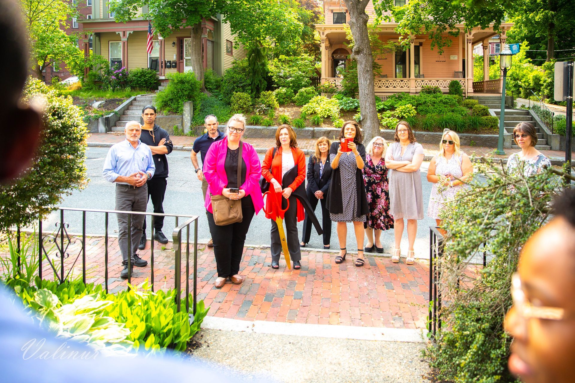 A group of people are standing on a sidewalk in front of a house.