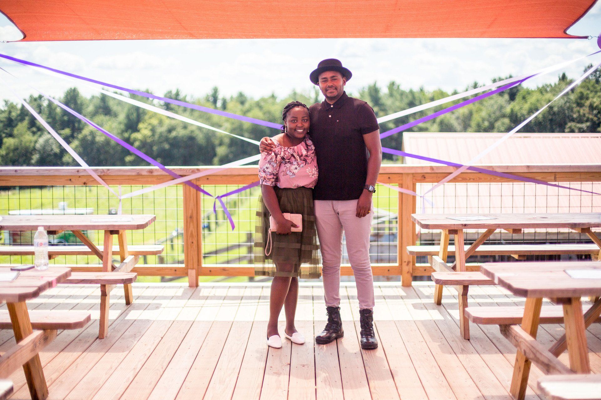 A man and a woman are standing on a deck with picnic tables.