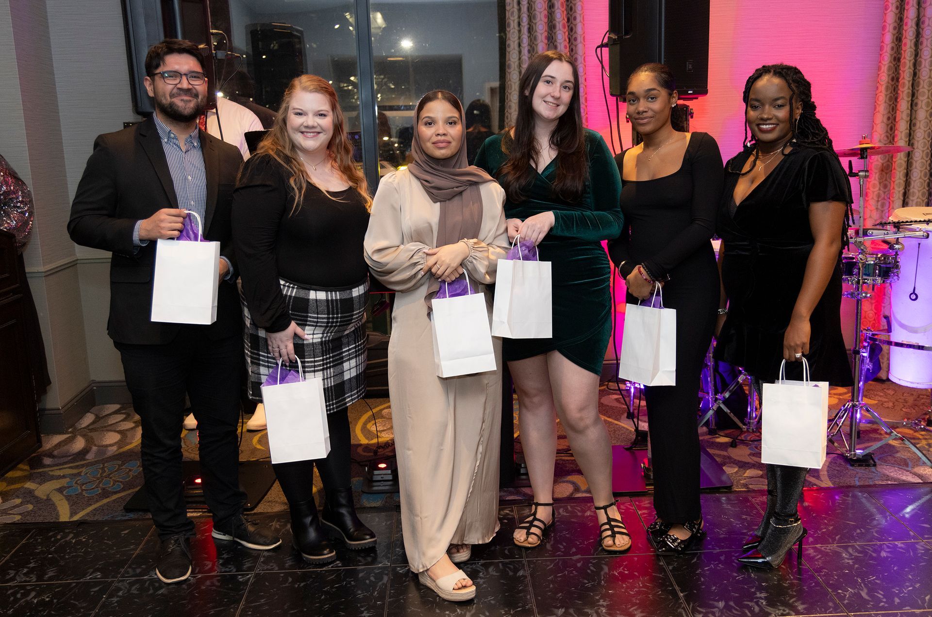 A group of people standing next to each other holding bags.