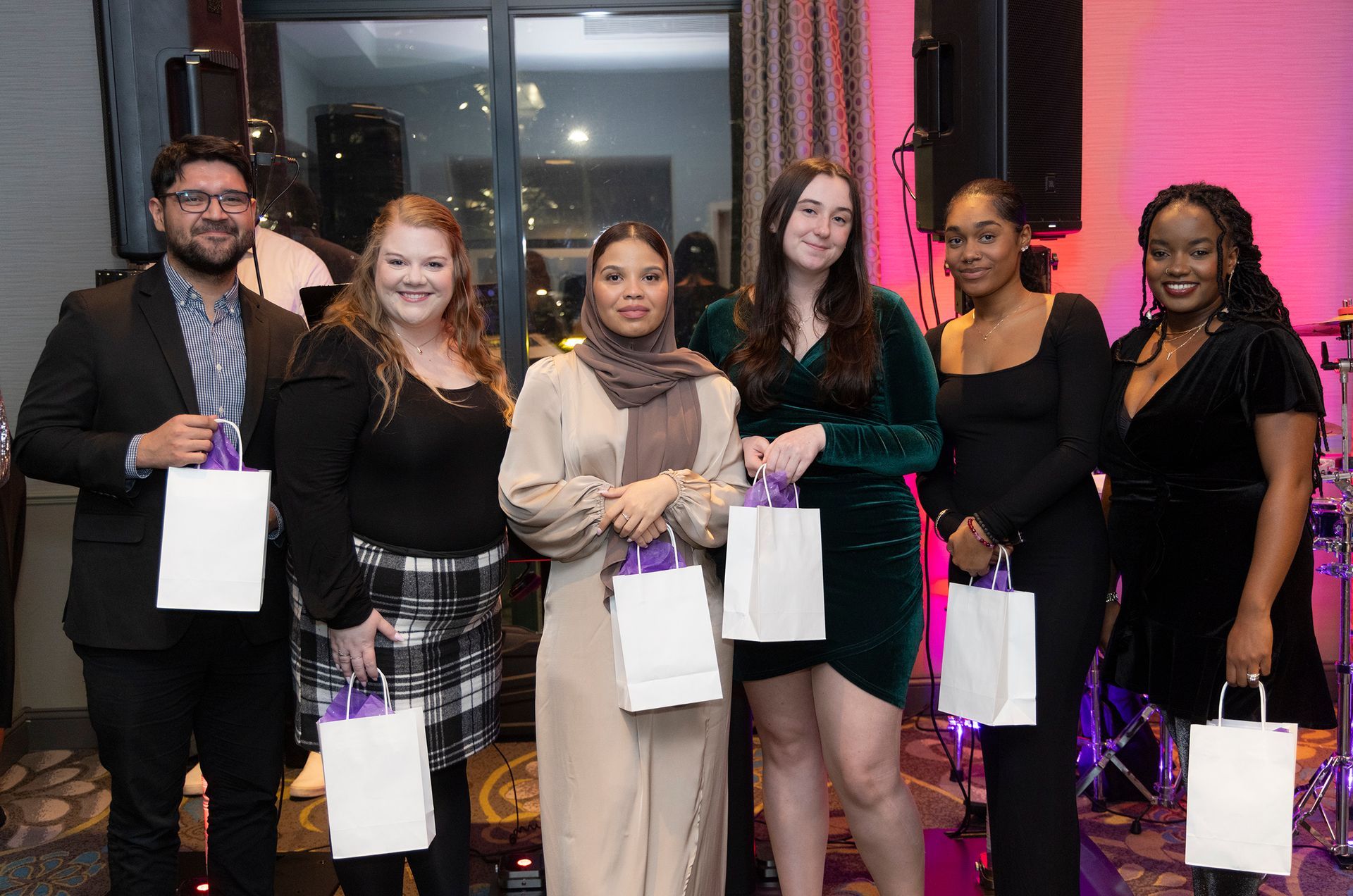 A group of people standing next to each other holding bags.