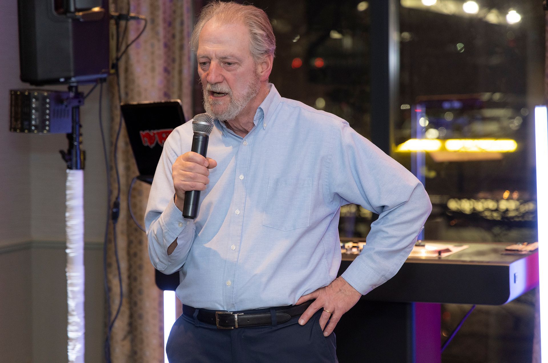 A man in a blue shirt is holding a microphone and talking into it.