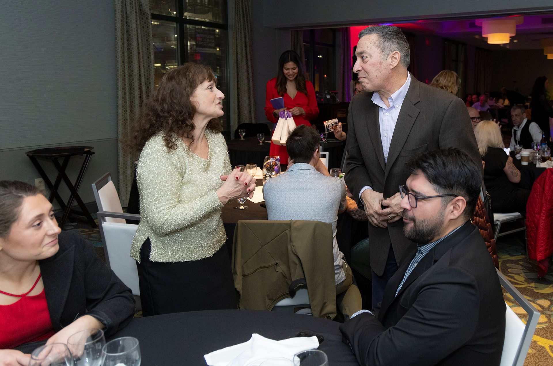 A group of people are sitting at a table talking to each other.