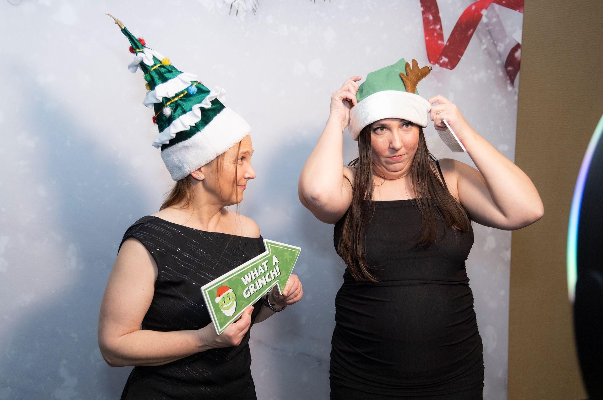 Two women wearing christmas hats are posing for a picture.