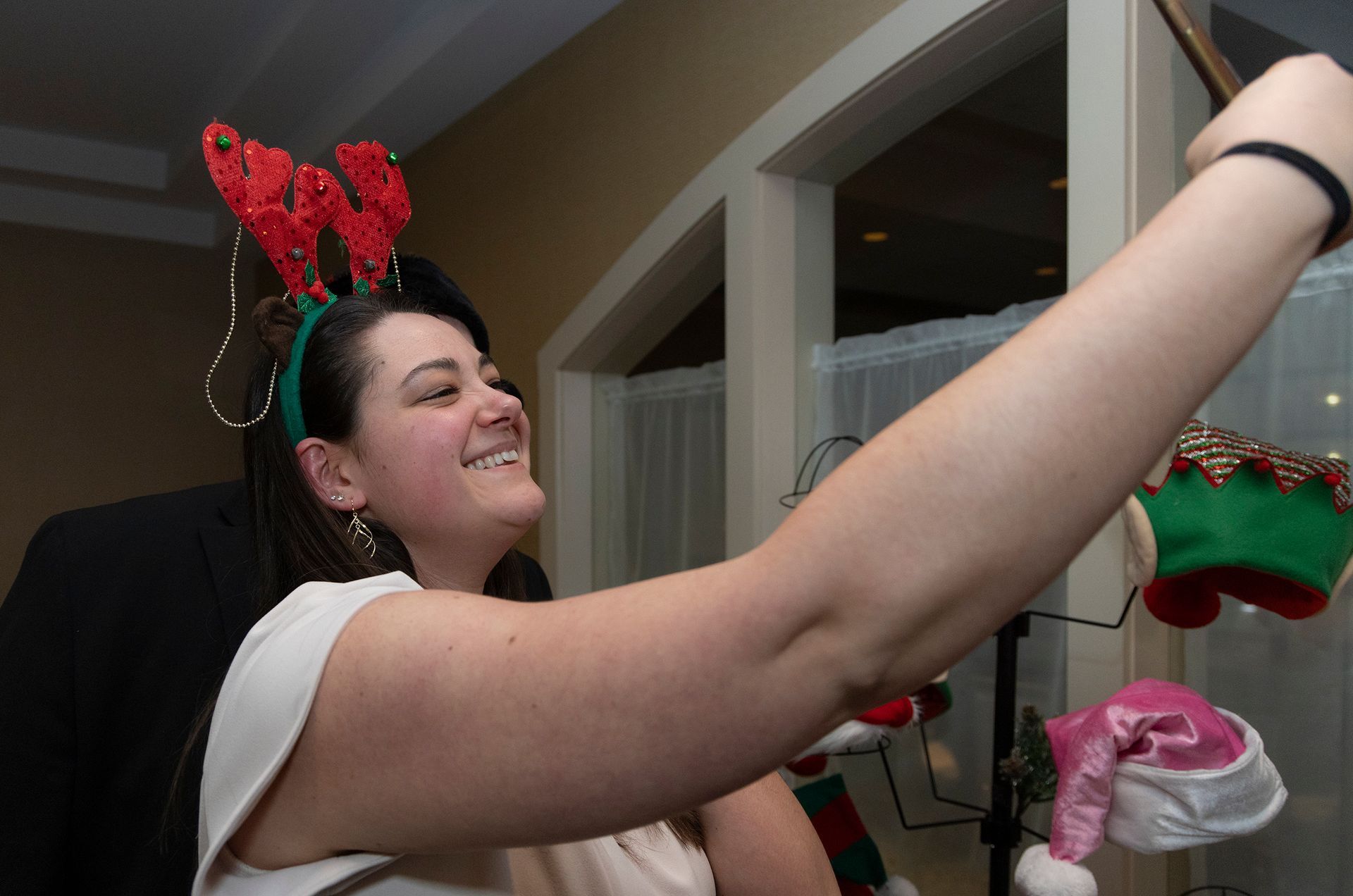 A woman wearing a reindeer headband is taking a selfie.