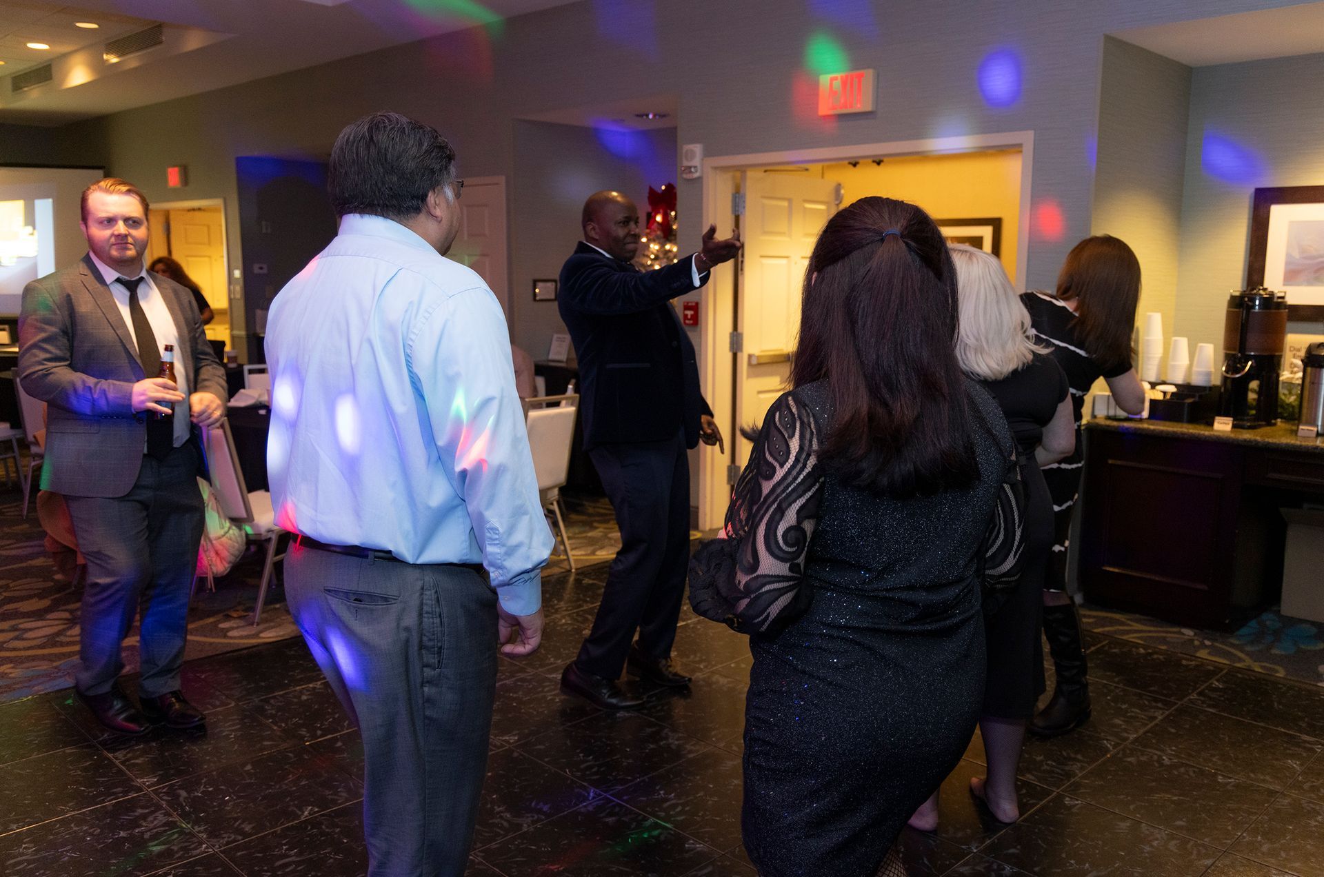 A group of people are dancing in a room with disco lights.