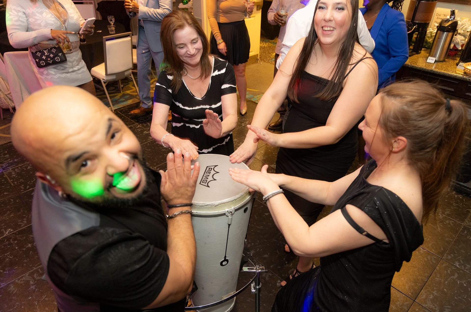 A group of people are playing a drum together at a party.