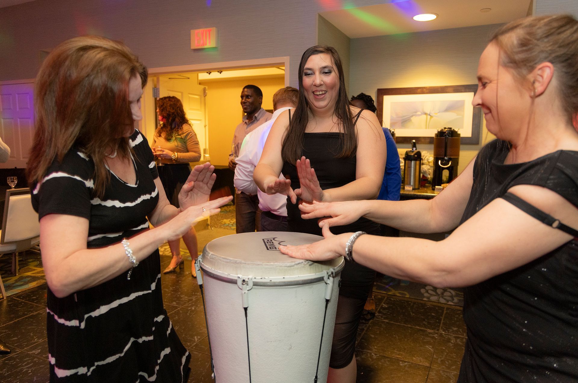 A group of women are dancing around a drum.