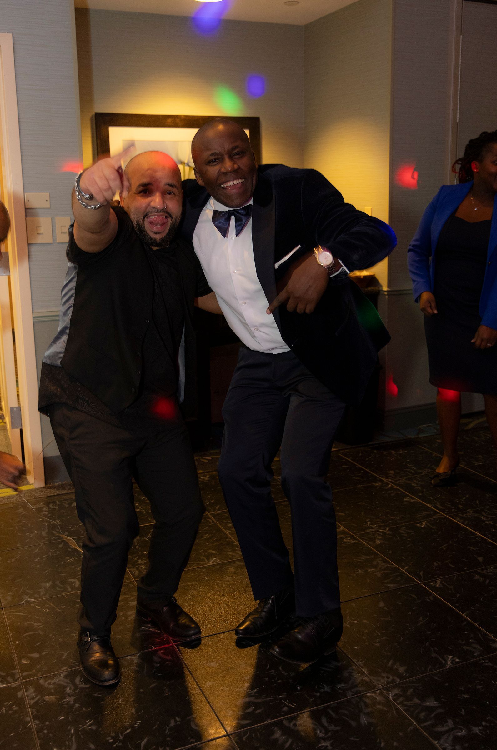 Two men are posing for a picture while dancing on a dance floor.