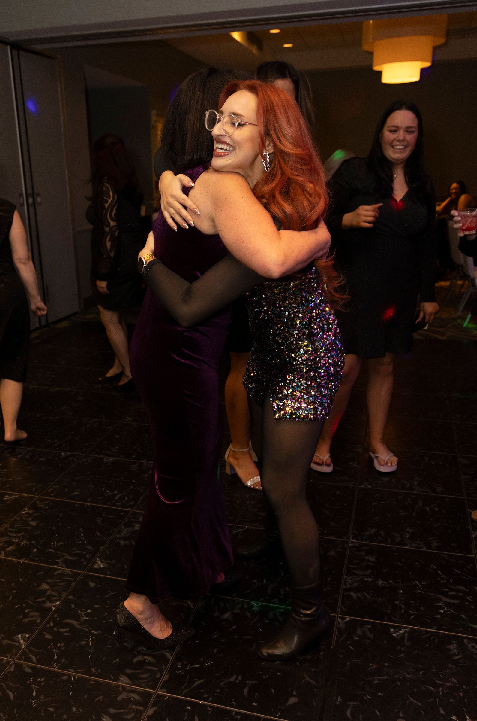 Two women are hugging each other while dancing at a party.
