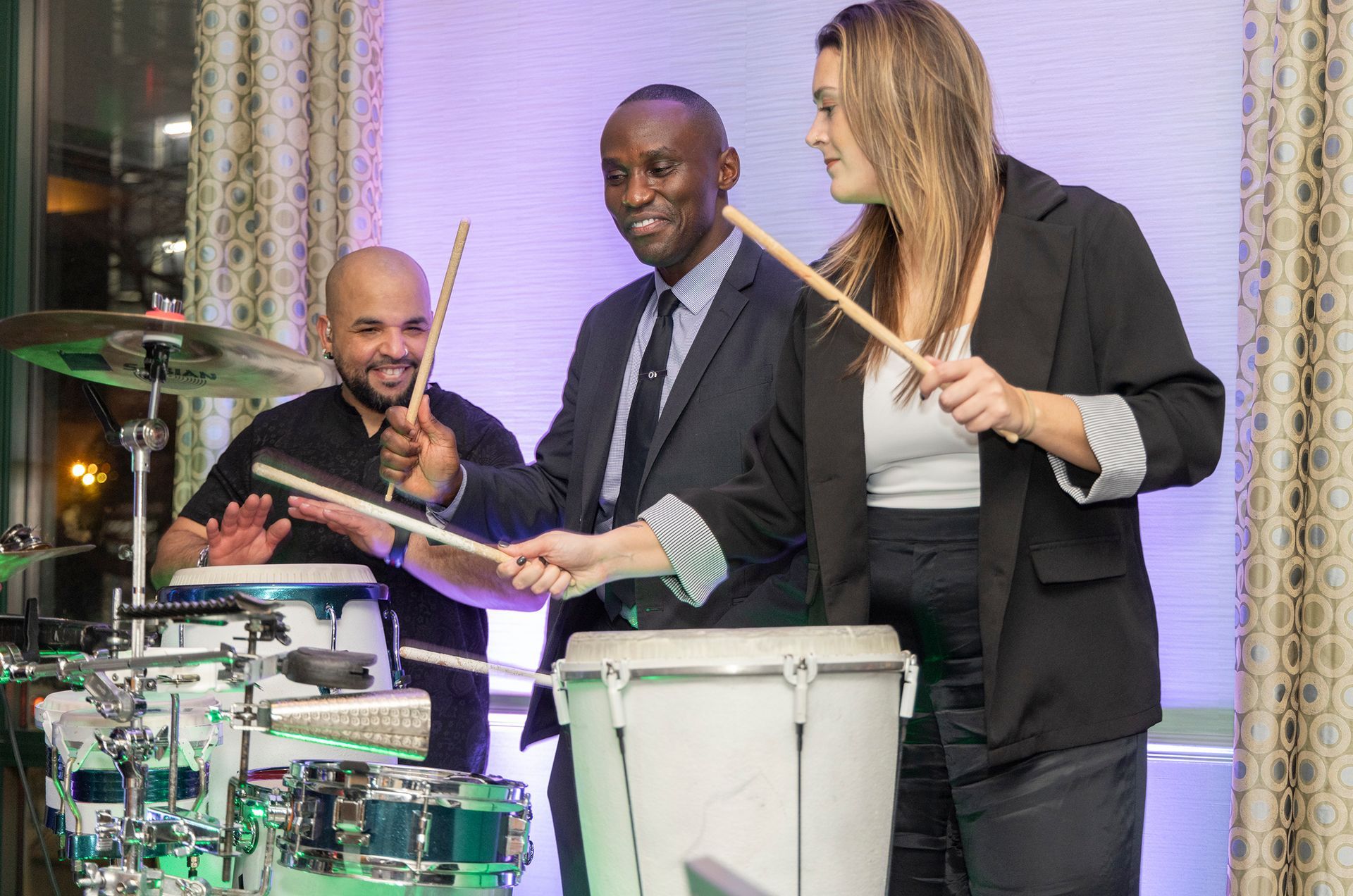 A group of people are playing drums in a room.