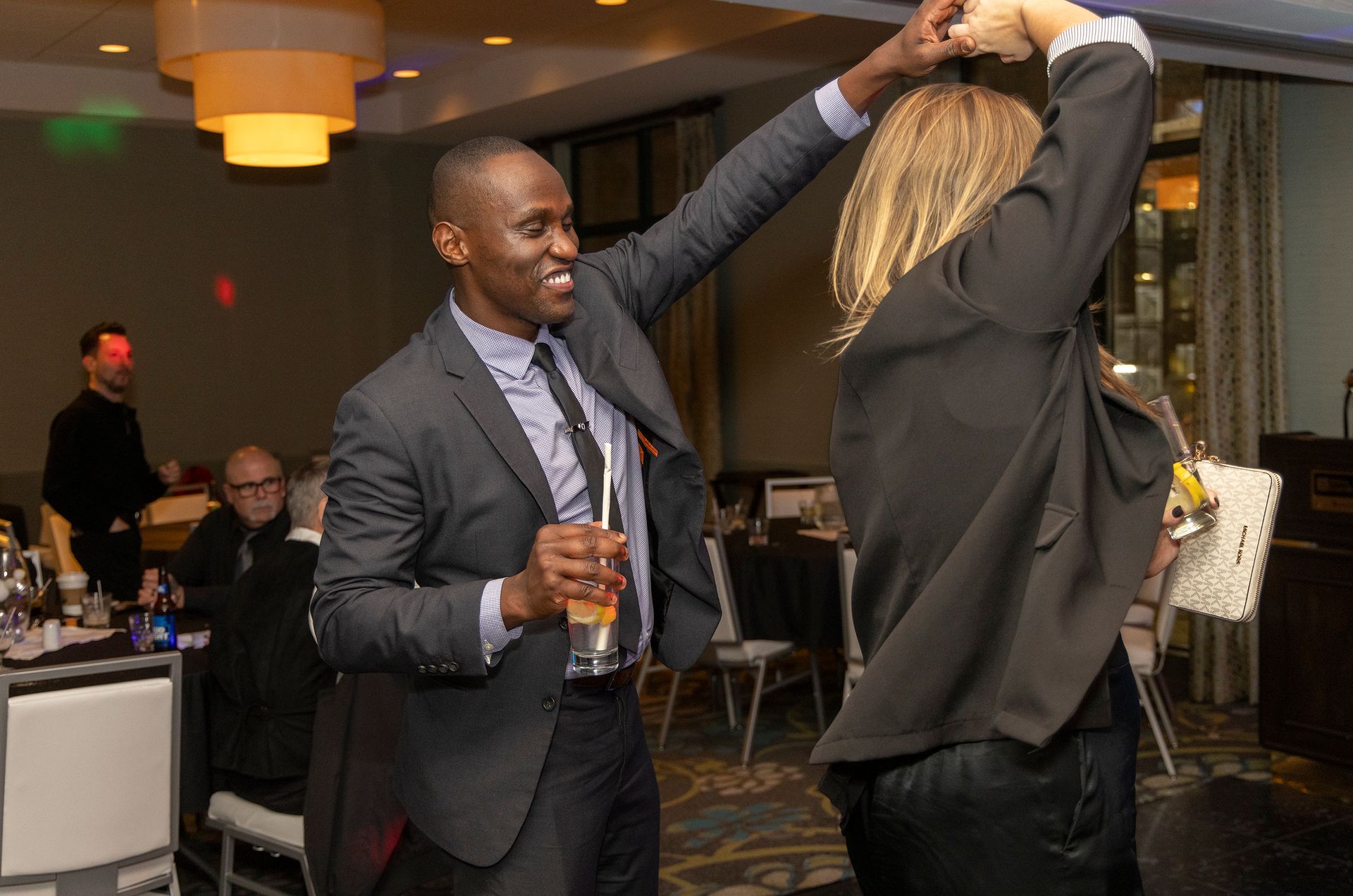 A man in a suit and tie is dancing with a woman in a room.