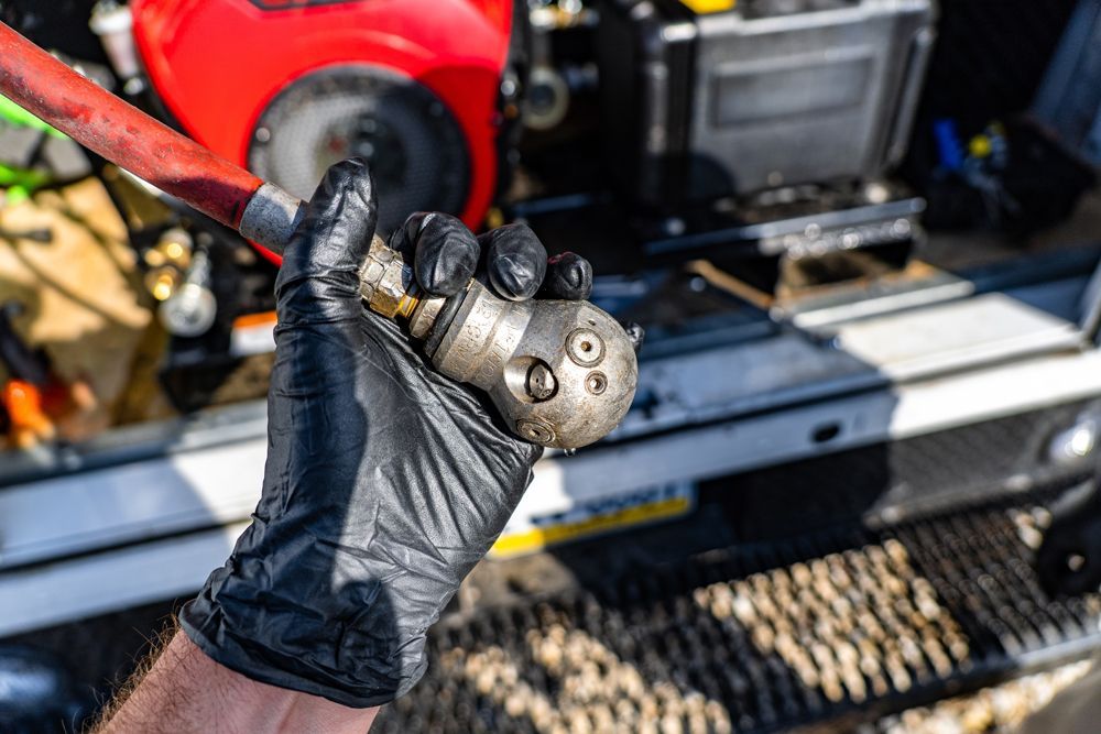 A person wearing black gloves is holding a hose in their hand.