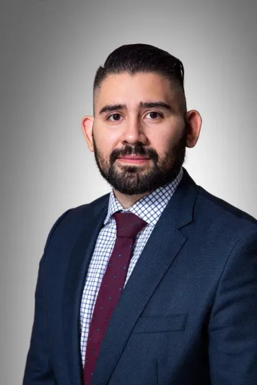 A bald man with a beard is wearing a suit and tie.