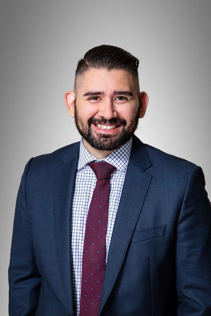 A man in a suit and tie is smiling for the camera.