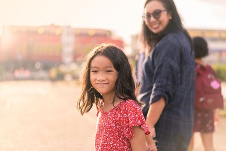 A woman is holding a little girl 's hand in a park.
