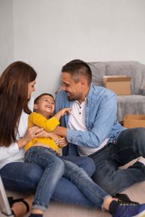 A family is sitting on the floor in their new home.