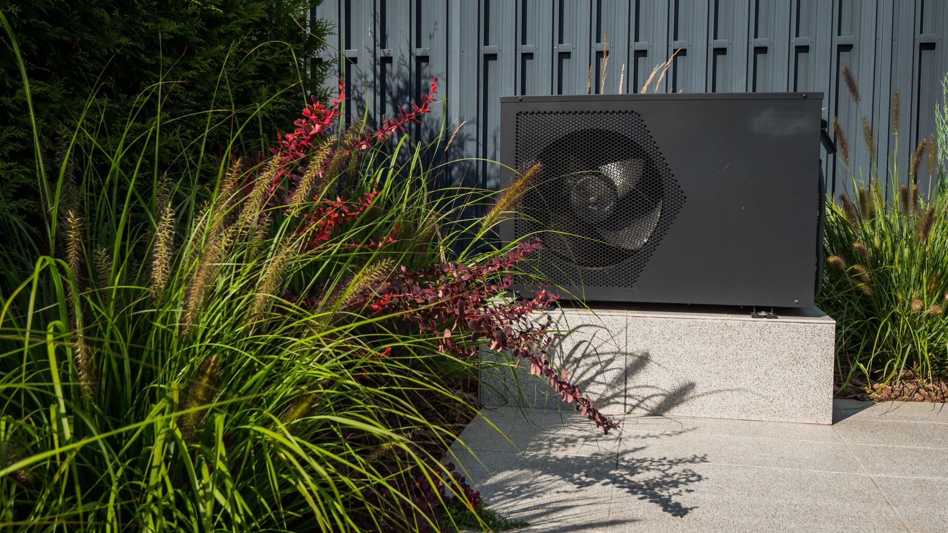 Black Heat Pump Unit on a Concrete Base, Surrounded — Clearwater Pools Hallidays Point in Old Bar, NSW