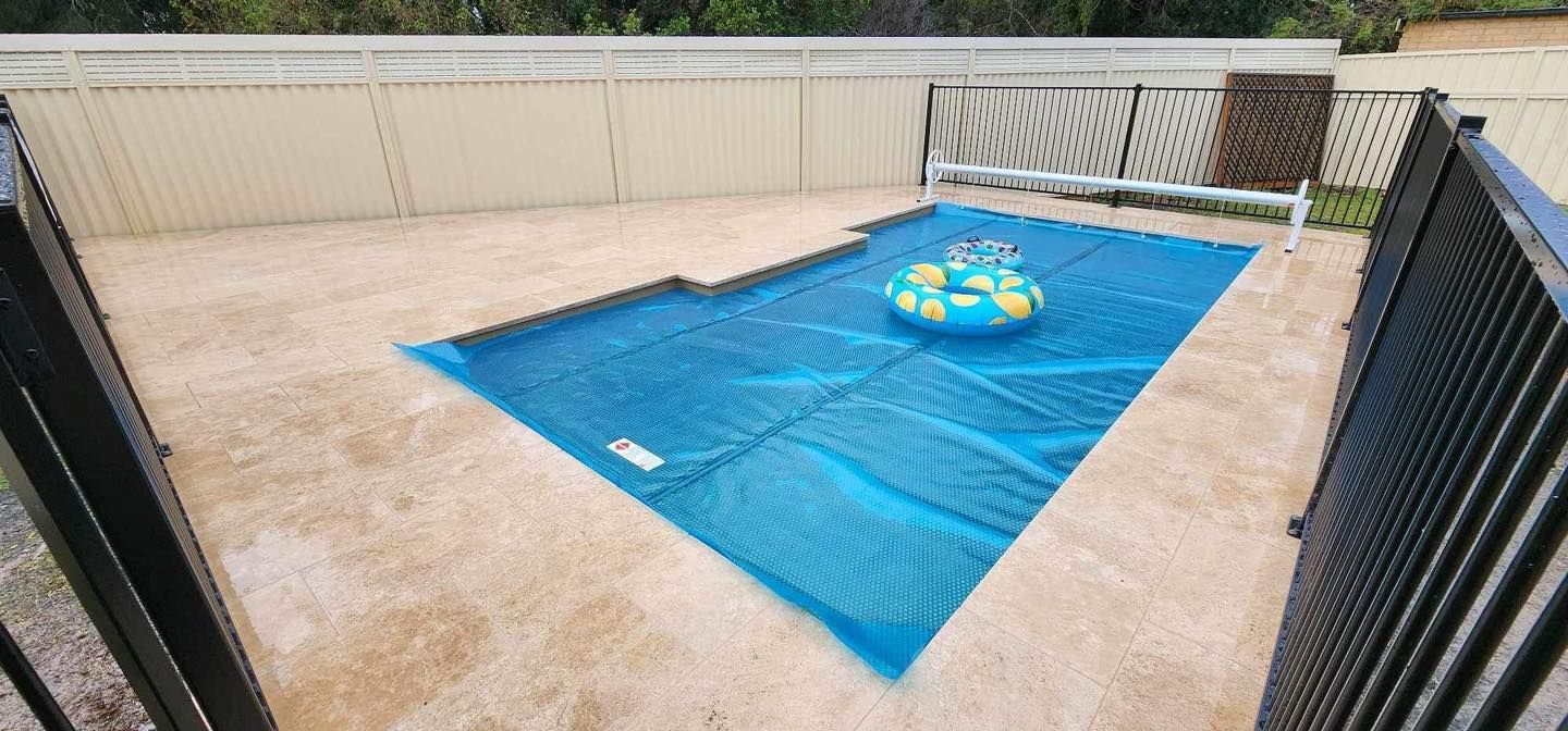 A Pool Covered with A Blue Blanket with A Yellow and Blue Float — Clearwater Pools Hallidays Point in Hallidays Point, NSW