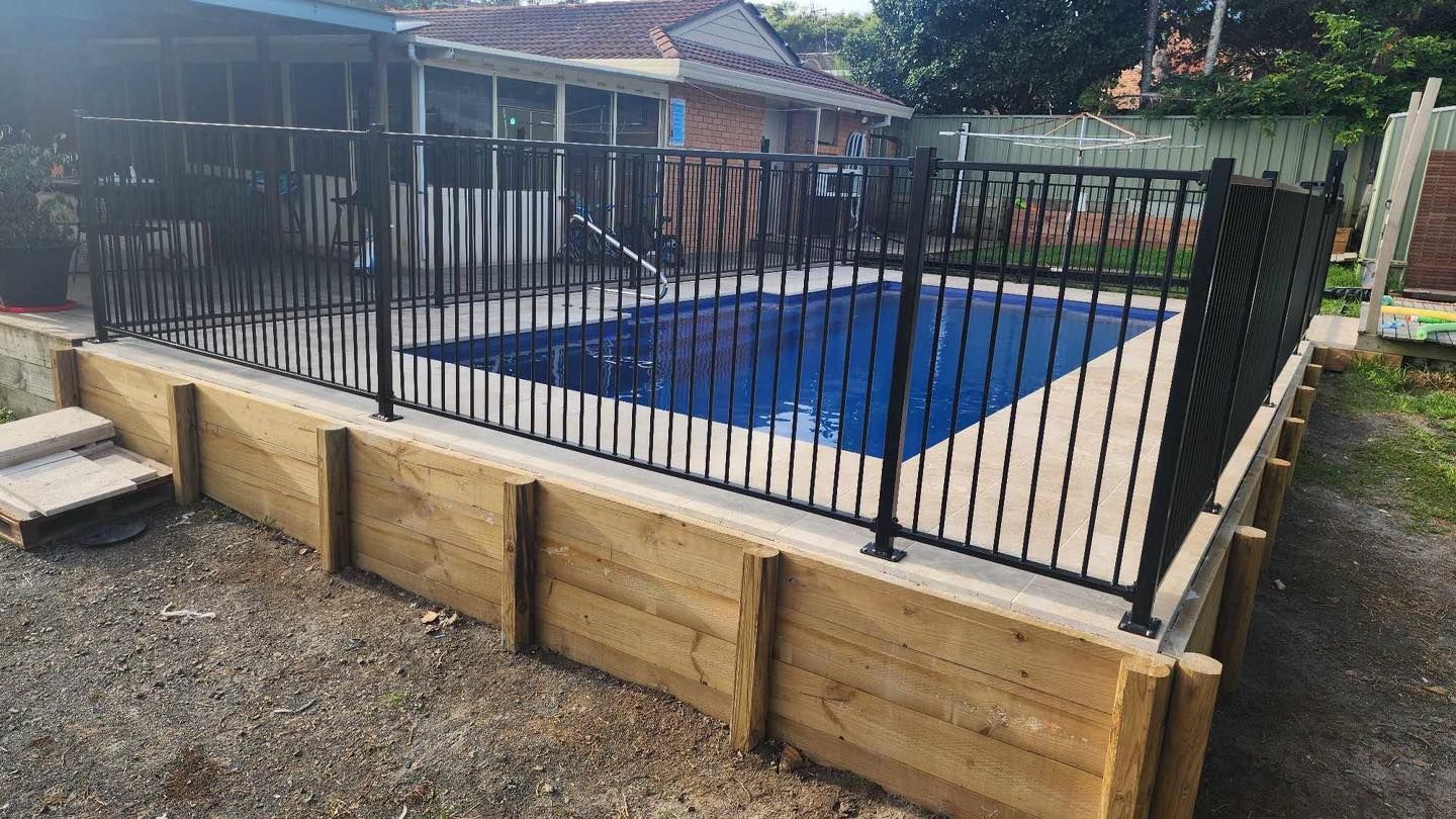 Black Fence Surrounding a Blue Pool, Set Within a Timber-retaining Wall — Clearwater Pools Hallidays Point in Taree, NSW
