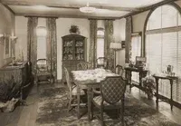 A black and white photo of a dining room with a table and chairs.