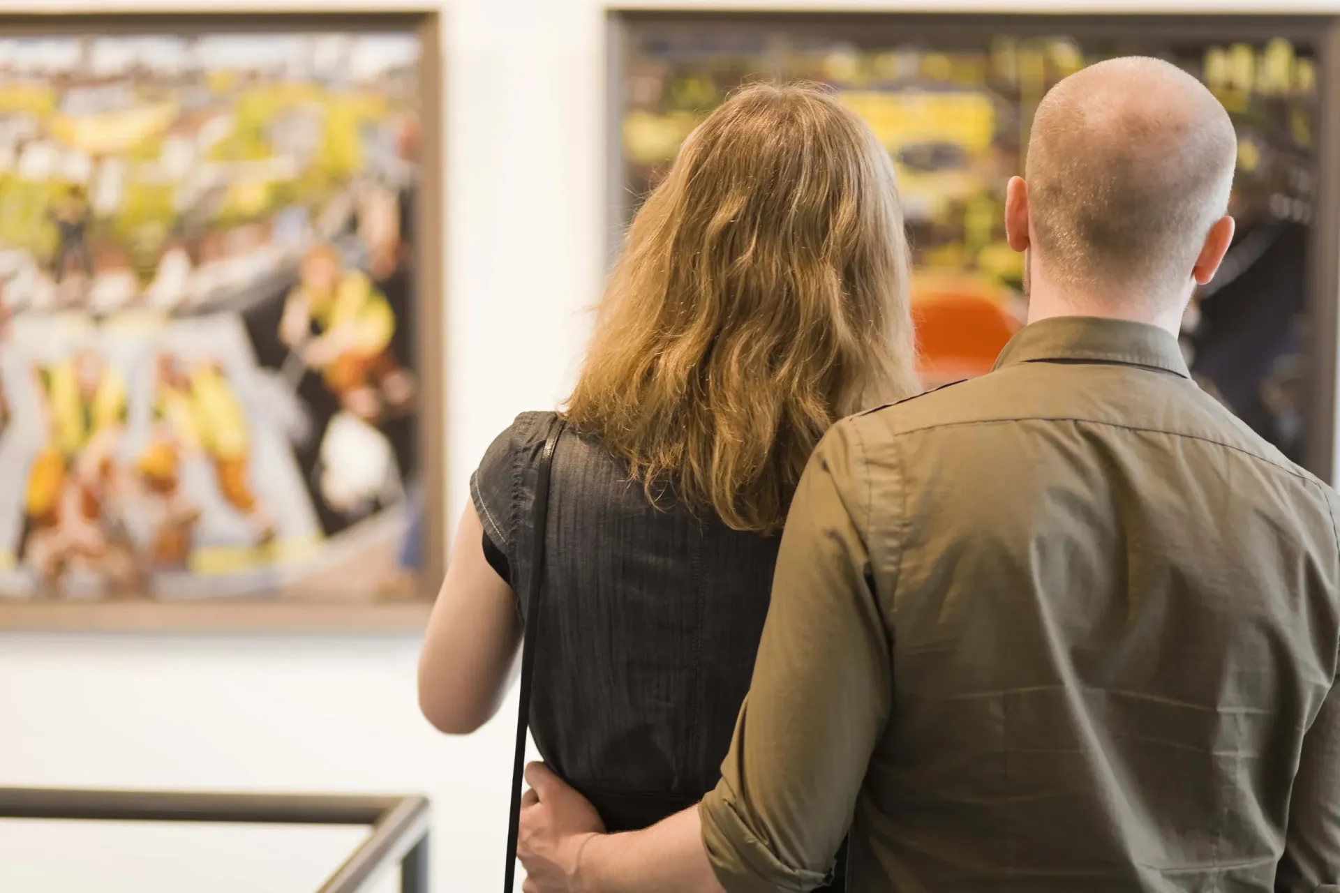 a man and a woman are looking at a painting in a museum