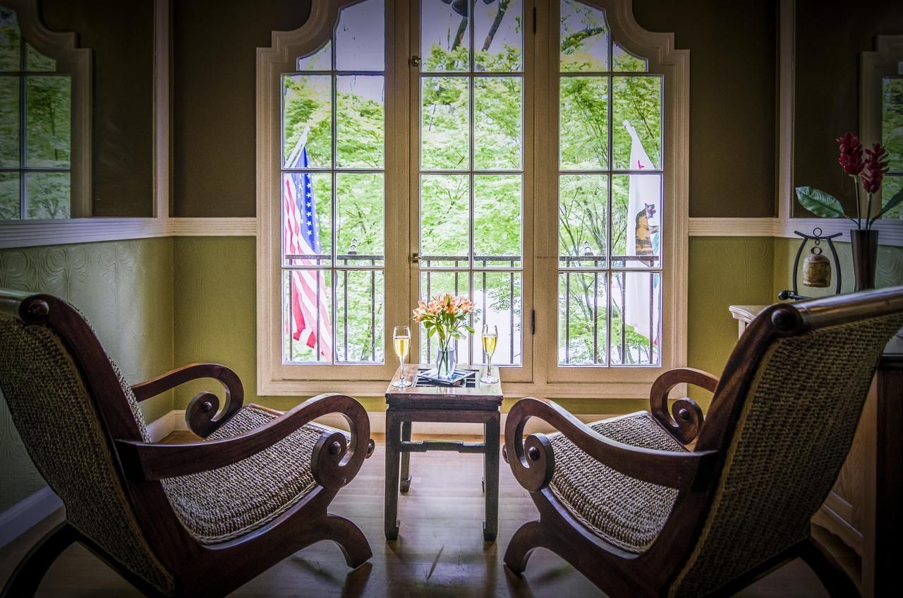 A room with two chairs and a table in front of a window.