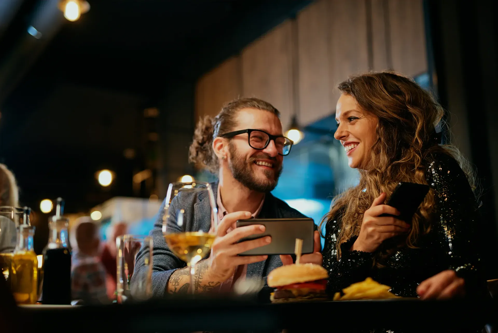 a man and a woman are sitting at a table in a restaurant looking at a cell phone